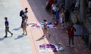 Venedors ambulants interactuen amb compradors en una plaça del front marítim