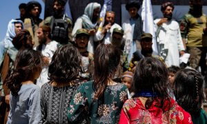 Niñas afganas observan a simpatizantes talibanes en el segundo aniversario de la caída de Kabul en una calle cerca de la embajada de EEUU en Kabul