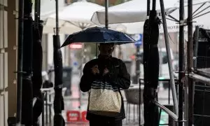 Varias personas se resguardan de la lluvia con paraguas, a 3 de septiembre de 2023, en Madrid.