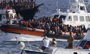 Migrantes rescatados llegan en un barco al puerto de Lampedusa entre dos barcos de turistas, a 18 de septiembre de 2023.