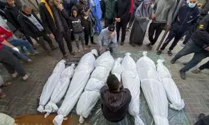 Un grupo de personas en la ciudad de Rafah rodea los cuerpos tapados de varias víctimas (algunas niños), al sur de la Franja de Gaza, tras reanudarse los bombardeos de Israel este 1 de diciembre de 2023.