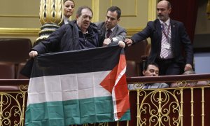 Un asistente despliega una bandera palestina durante el pleno del Congreso en el que comparece el ministro de Asuntos Exteriores, José Manuel Albares, a 5 de diciembre de 2023.