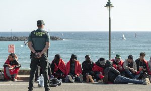 Un agente de la Guardia Civil custodia a un grupo de personas migrantes llegadas en patera a la costa de Teguise, en Lanzarote, a 26 de diciembre de 2023.