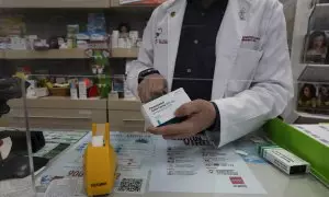 Un farmacéutico recorta el código de barras de una caja de Paracetamol en su farmacia, en Madrid a 20 de abril de 2020