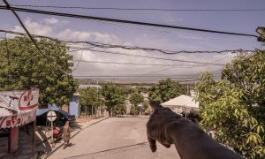 Emilio Pérez, padre de Inés Pérez, que sufrió la violencia policial durante la expulsión de Tabaco, muestra la mina El Cerrejón desde la ventana de la nueva casa familiar en Albania, La Guajira, Colombia, en julio de 2023.