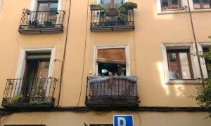 Marina, de 94 años, saluda desde su balcón a los colectivos vecinales que han ayudado a frenar su desahucio.