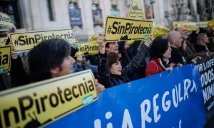 Varias personas protestan con carteles durante una manifestación contra la mascletá programada por el alcalde de Madrid en Madrid Río.