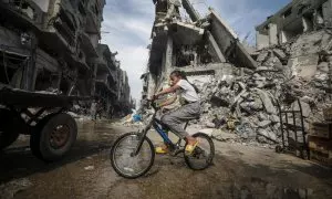 Una niña monta en bicicleta junto a edificios destruidos en una calle del campo de refugiados de Nuseirat (Franja de Gaza) el 5 de abril de 2024.