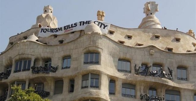 Las juventudes de la CUP cuelgan una pancarta contra el turismo en la fachada de La Pedrera