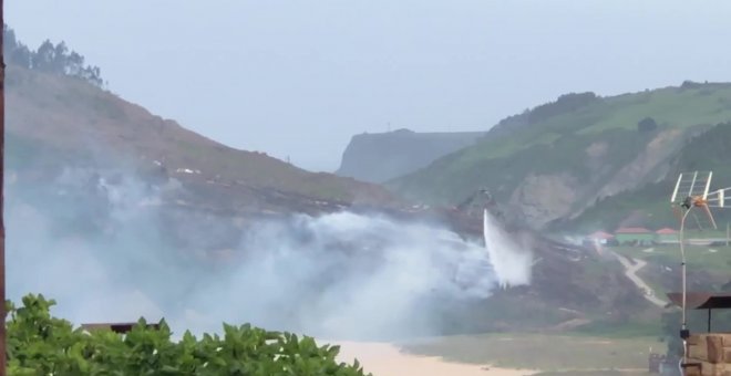 Labores de extinción del incendio en la playa de Rodiles