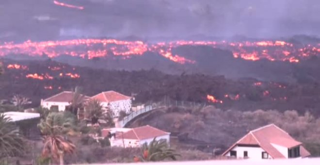 Vecinos desalojados observan su casa a punto de ser engullida