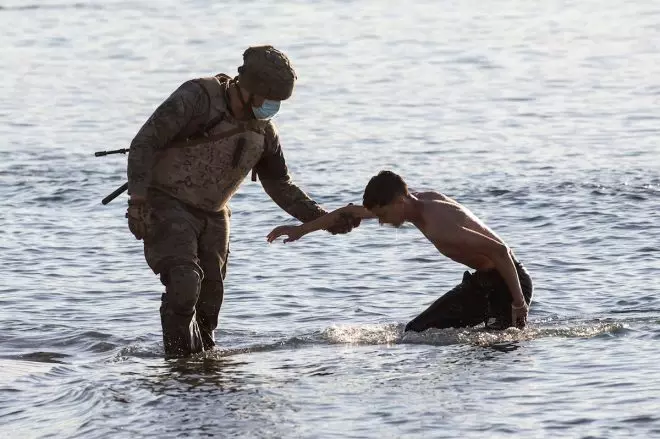 Un soldado del ejército ayuda a un migrante a su llegada a la playa de El Tarajal. — EFE