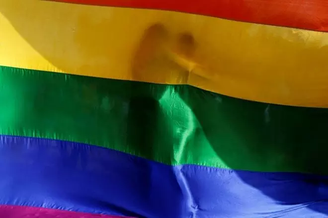 Dos personas se abrazan tras una bandera LGTBI.- Danish Siddiqui / Reuters