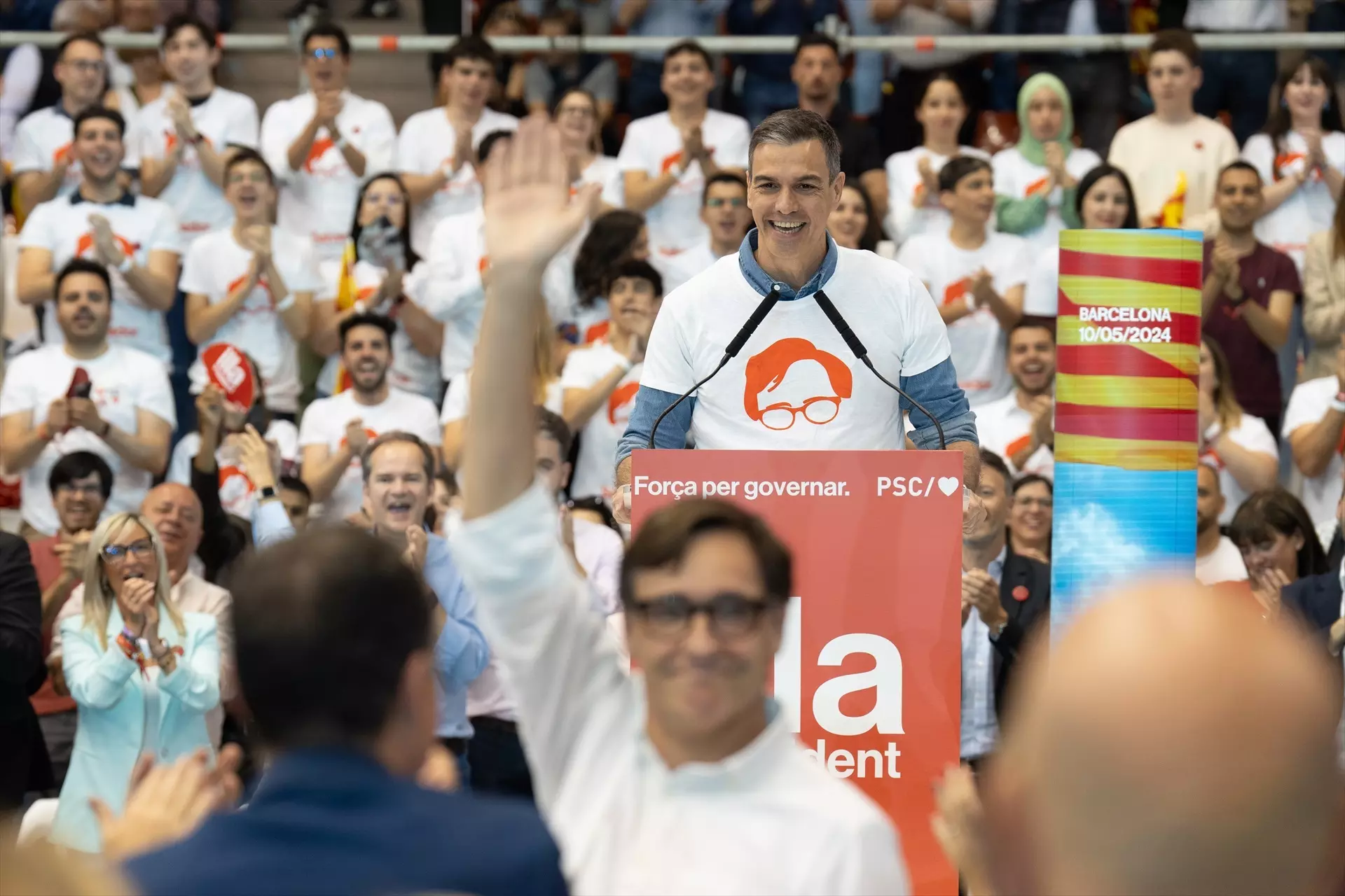 Pedro Sánchez, con la camiseta de Salvador Illa, mientras el candidato del PSC saluda. — Europa Press