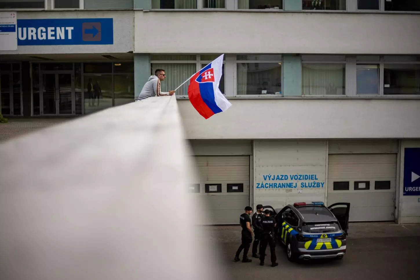 Un hombre ondea la bandera nacional eslovaca frente al hospital donde el primer ministro eslovaco, Robert Fico, está siendo tratado después de recibir varios disparos el pasado 15 de mayo. — MARTIN DIVISEK / EFE