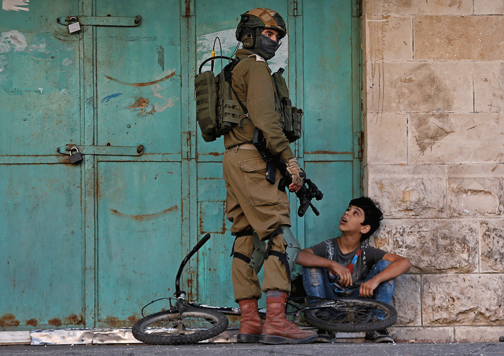 Un soldado israelí detiene a un menor palestino en unas protestas en Hebrón, en Cisjordania. REUTERS/Mussa Qawasma
