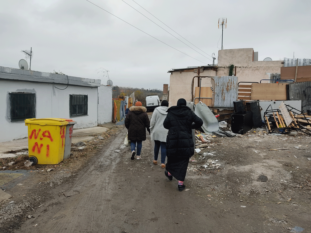 Las tres mujeres caminan hacia sus casas en una calle sin asfaltar y repleta de charcos y barro. Las tres mujeres caminan hacia sus casas en una calle sin asfaltar y repleta de charcos y barro.