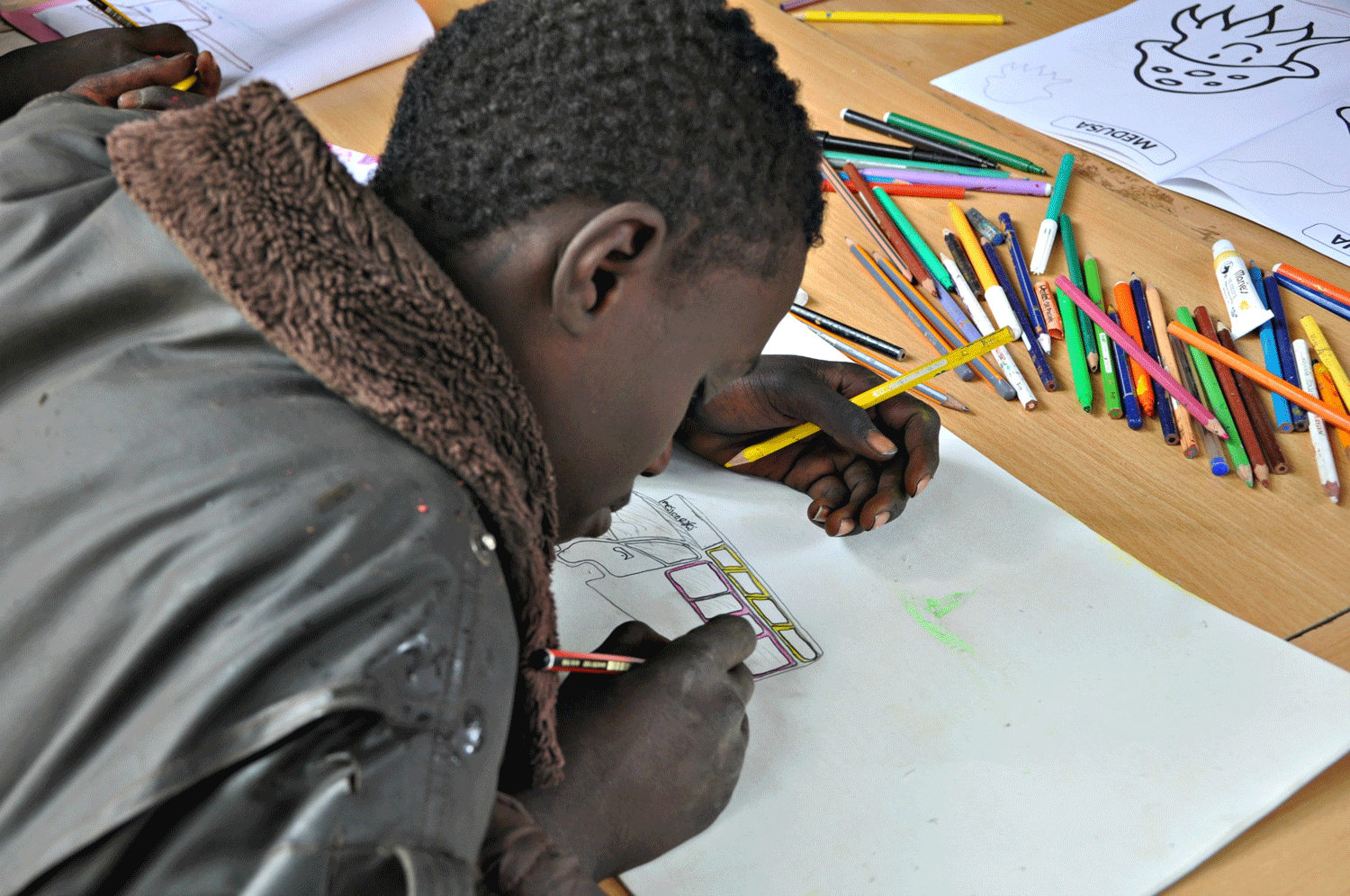 Un niño de la calle dibuja un matatu o furgoneta para viajeros en un taller de dibujo en Nairobi. EFE