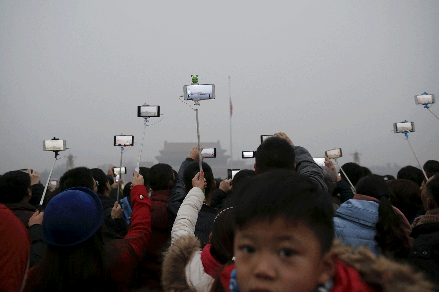 Un grupo de personas graba la ceremonia de izado de bandera en Pekín en medio de la grave contaminación que provocó la primera alerta roja en la ciudad. REUTERS Un grupo de personas graba la ceremonia de izado de bandera en Pekín en medio de la grave contaminación que provocó la primera alerta roja en la ciudad. REUTERS