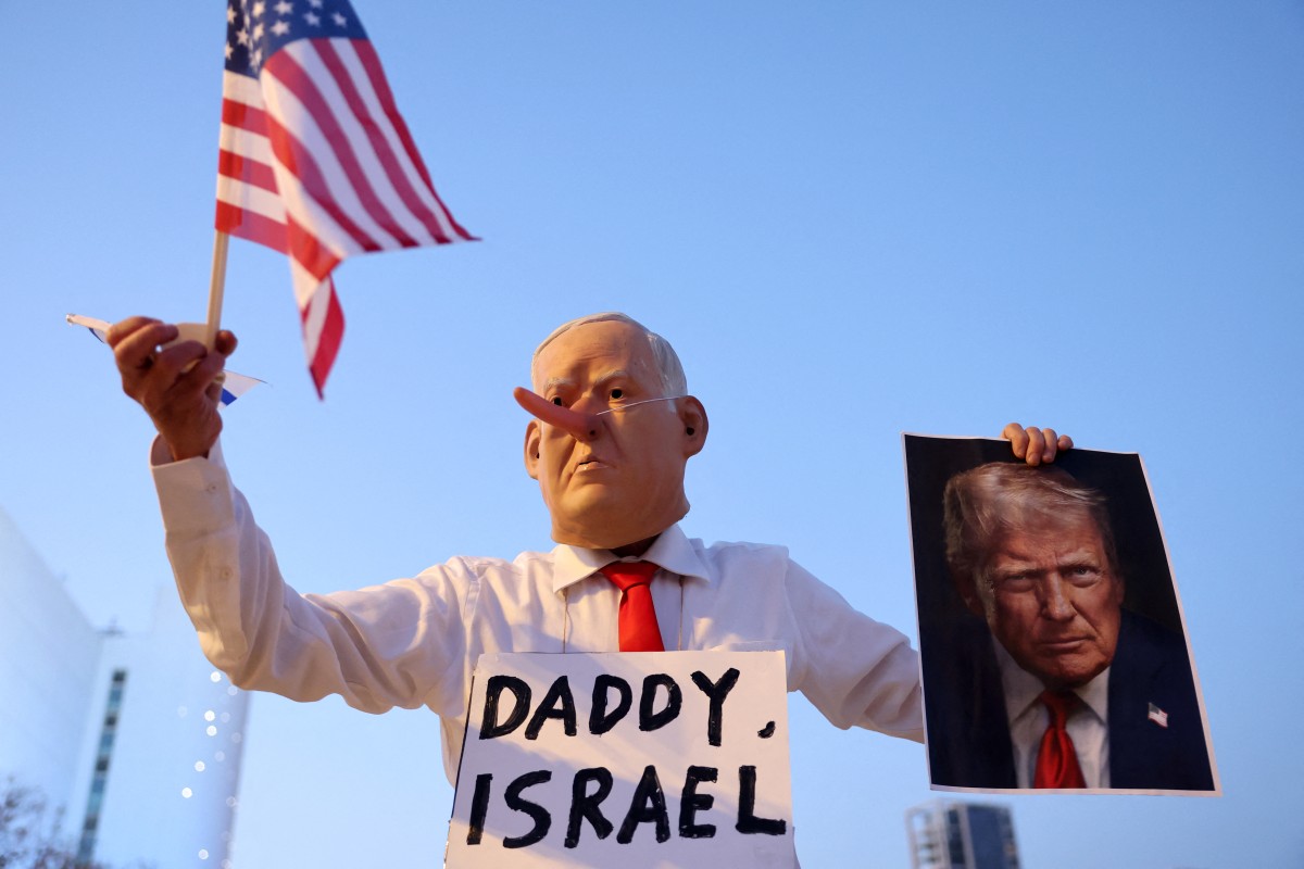 Un activista israelí disfrazado del primer ministro israelí Benjamin Netanyahu y con una imagen del presidente de EEUU, Donald Trump, y la bandera estadounidense en la mano, se manifiesta en la plaza HaBima (Tel Aviv) contra la guerra en curso con Irán y contra el gobierno israelí (25.04.26)